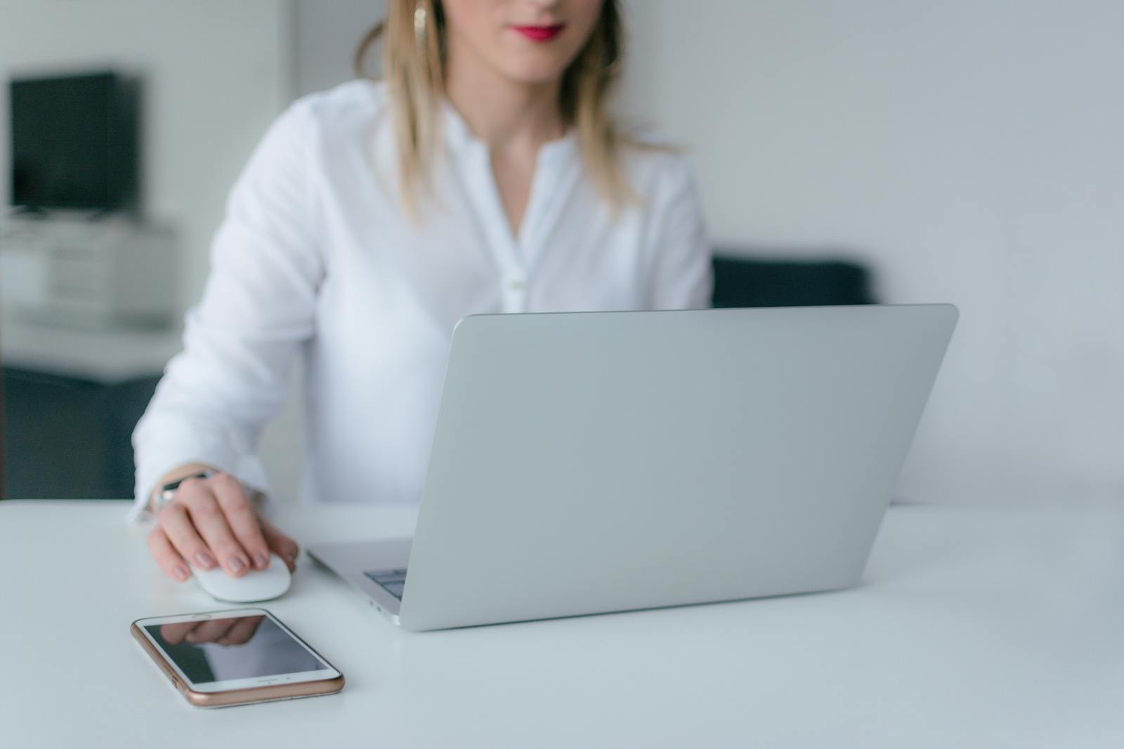 A woman working at a desk using a laptop and smartphone, exemplifying remote work.