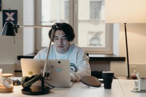 Focused young man working at his desk with a laptop in a contemporary office.